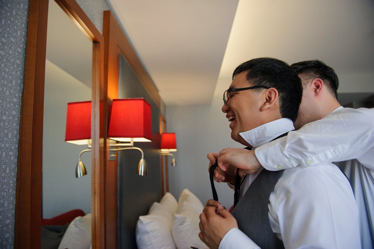 Groomsman helping the groom with his tie knot